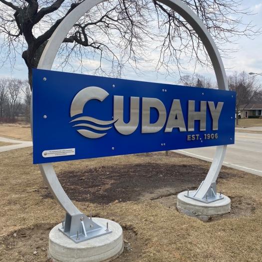 Blue “Cudahy Est. 1906” welcome sign displayed outdoors along a roadside in Cudahy, Wisconsin.