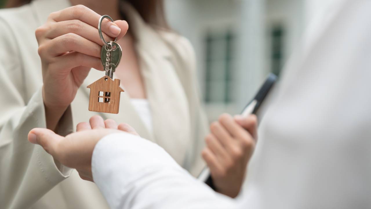 Real estate agent handing over house keys to a buyer, symbolizing success in financing a home in Aspen.