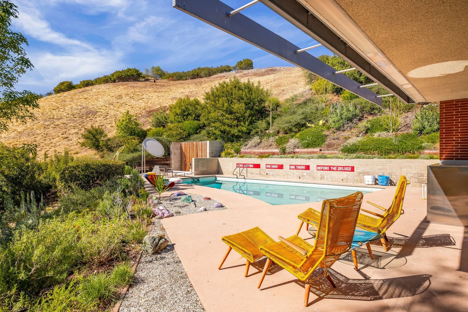 The original pool and terrace at the Sale House, sheltered beneath a deep roof overhang with canyon views beyond.