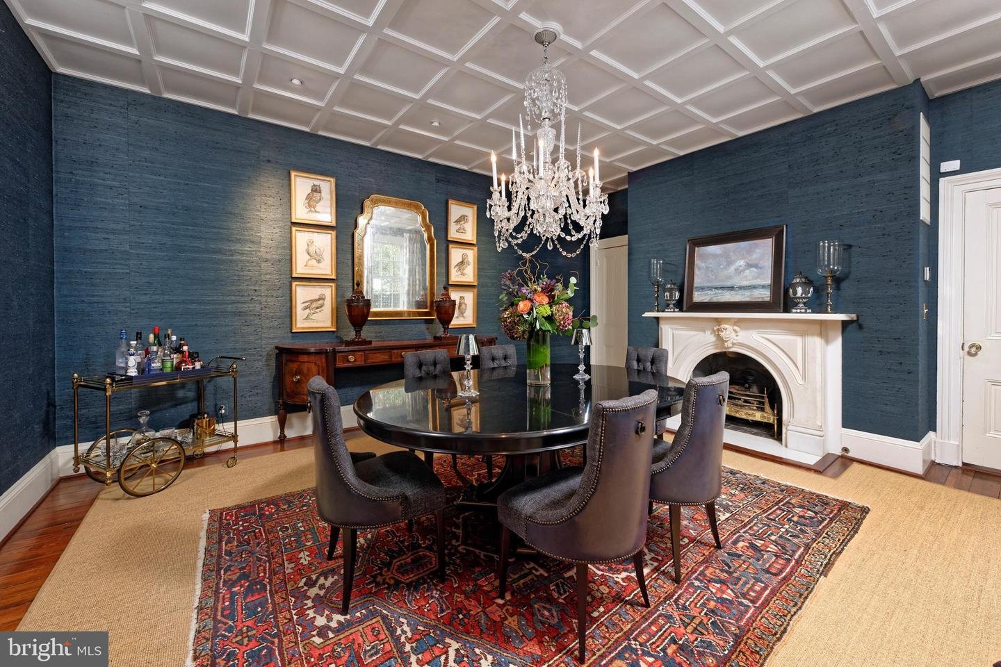 Formal dining room with a crystal chandelier, deep blue walls, and a white fireplace.