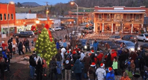 Crowds gather around a lit Christmas tree at a downtown holiday celebration.