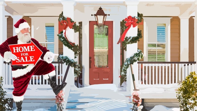 Santa holds a HOME FOR SALE sign outside a snow-covered house decorated for the holidays.
