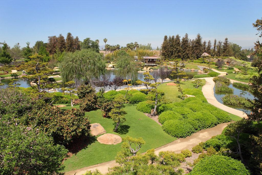 Aerial view of The Japanese Garden at Woodley Park in Van Nuys, San Fernando Valley, featuring lush green landscaping, winding pathways, and serene ponds under a bright blue sky.