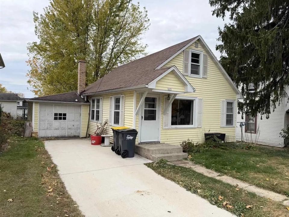 Yellow-sided house with an attached garage and concrete driveway.