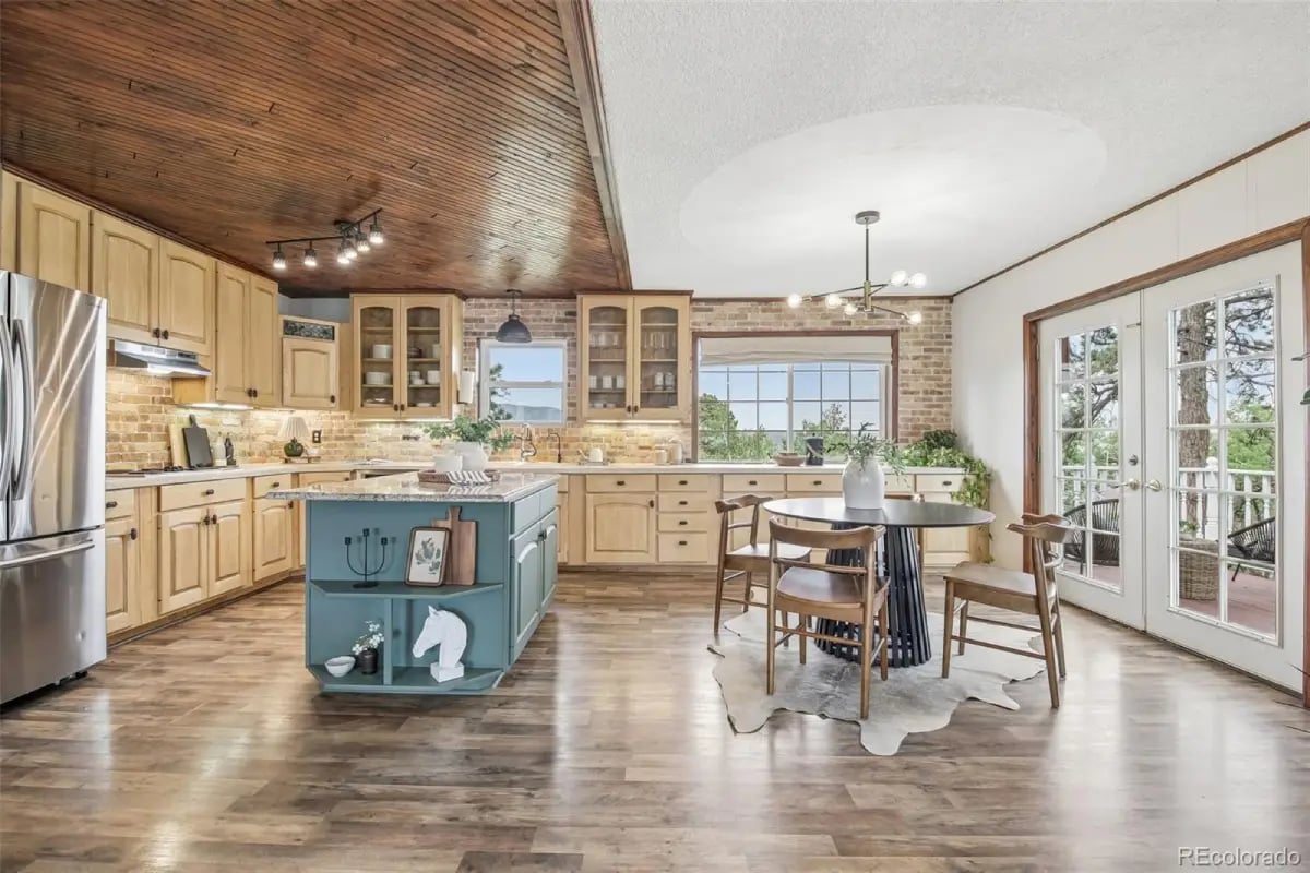 Spacious kitchen and dining room with a teal island, brick accent wall, and deck access at 278 Overlook Drive.