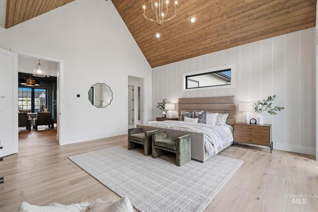 Staged bedroom with a king bed, pale wood floors, and a vaulted wood-plank ceiling.