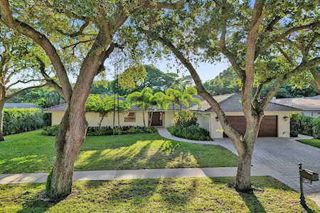 Single-story home with an attached garage, mature shade trees, and a front lawn.