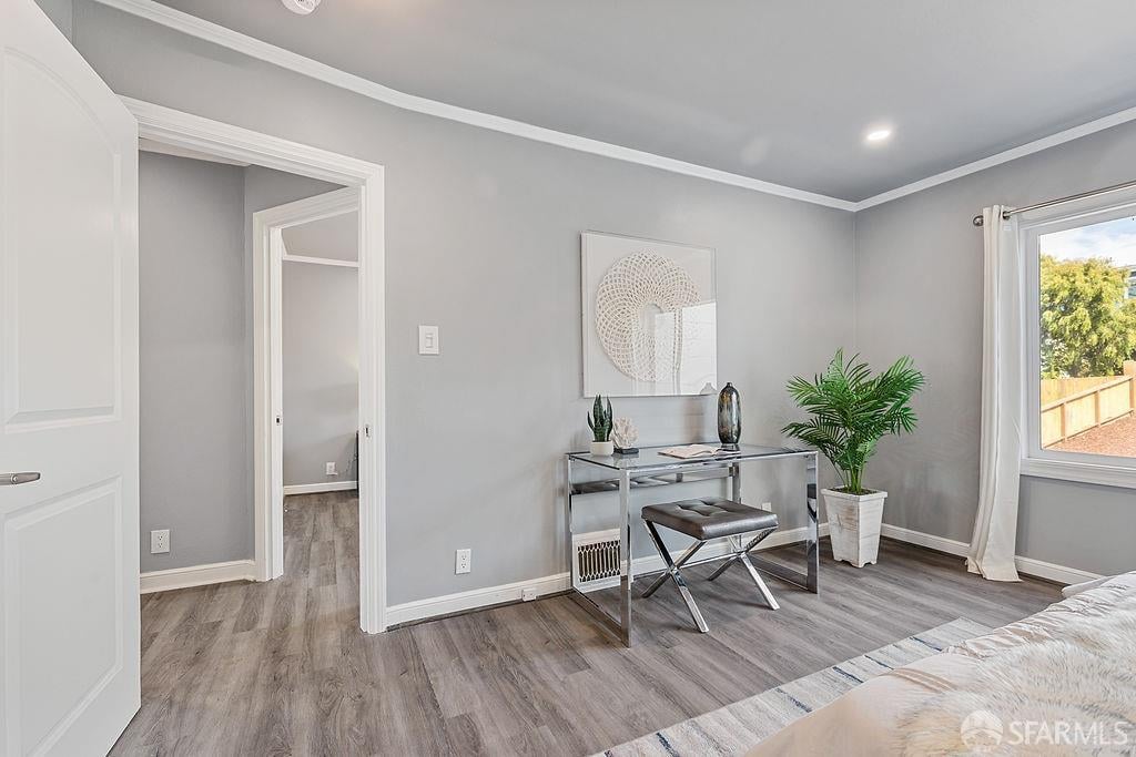 Staged bedroom with gray walls, a console table, potted plants, and a window overlooking a fenced yard.