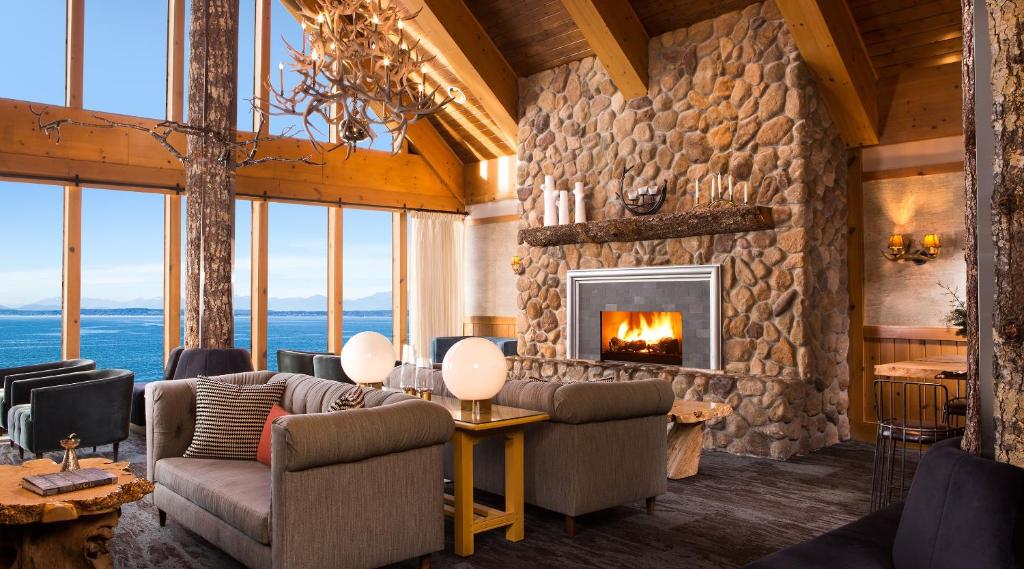 Living room with vaulted timber ceiling, stone fireplace, and ocean views.