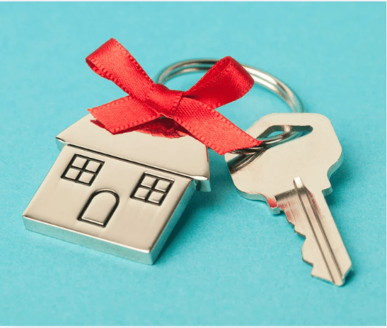 House-shaped keychain and metal key tied with a red bow