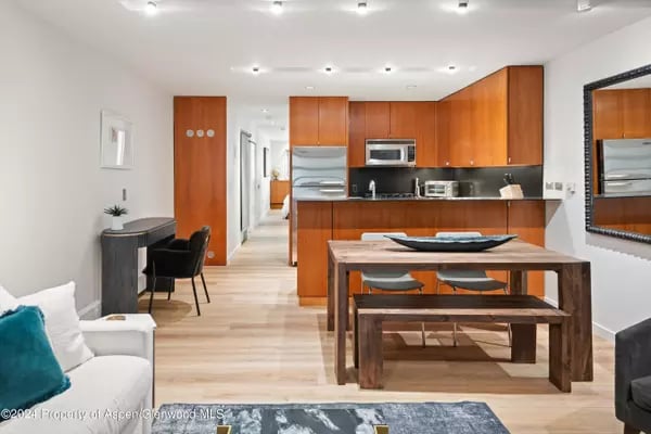 Open-plan kitchen and dining area with warm wood cabinets, stainless steel appliances, and a large dining table.