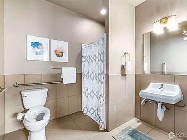 Bathroom with a toilet, wall-mounted sink, and patterned shower curtain.