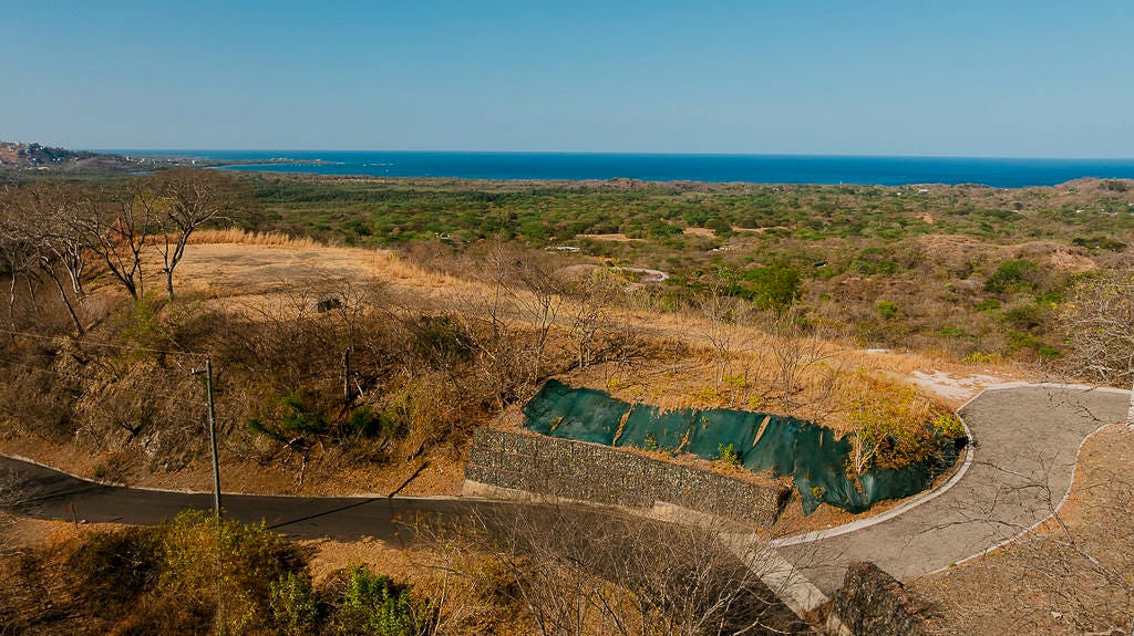 Coastal land parcel with a paved access road, retaining wall, and ocean view.