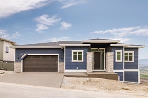 Contemporary blue home with stone accents, a covered entry and double garage.