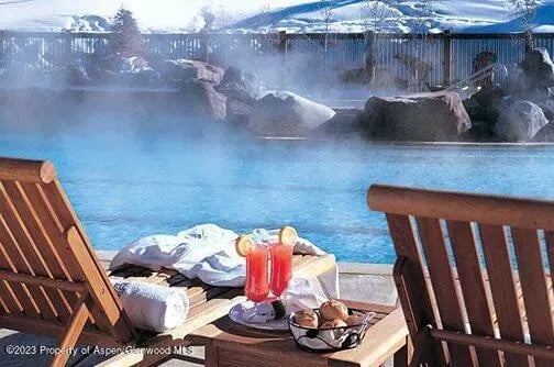Outdoor hot tub with snowy mountain views, lounge chairs, drinks and snacks.