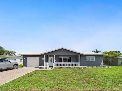 Single-story gray home with a covered porch, attached garage, and broad front lawn.