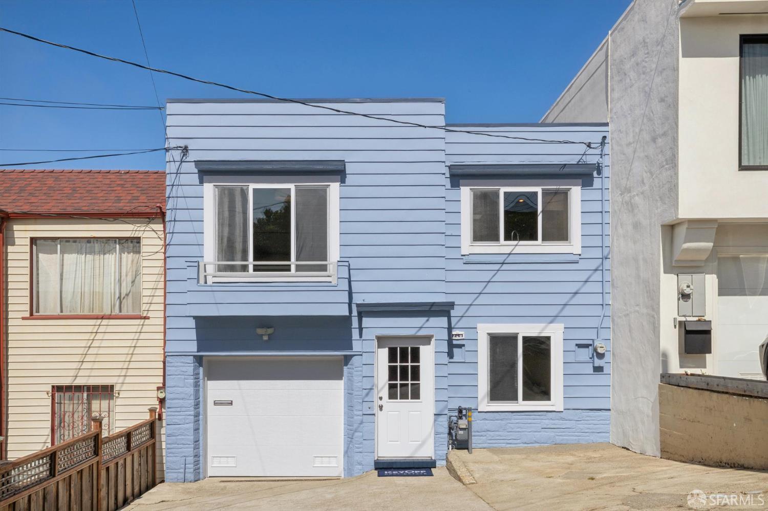 Blue two-story house with white trim, an attached garage, and a concrete driveway.