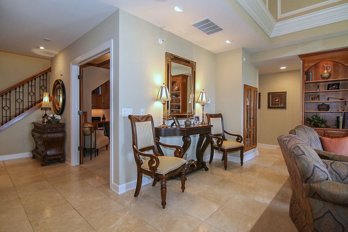 Penthouse foyer with tiled floors, wrought-iron staircase railing, and an ornate console table beneath a mirror.