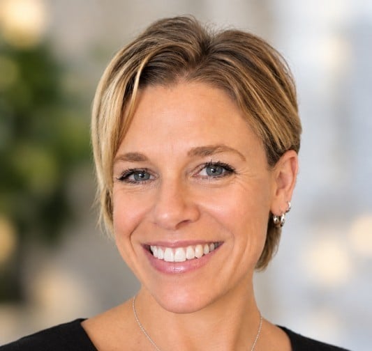 Dori Botts smiling in a headshot, with short blonde hair and hoop earrings.