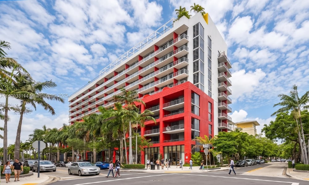 The Standard Residences, a white high-rise with a red lower facade and balconies on a palm-lined street.