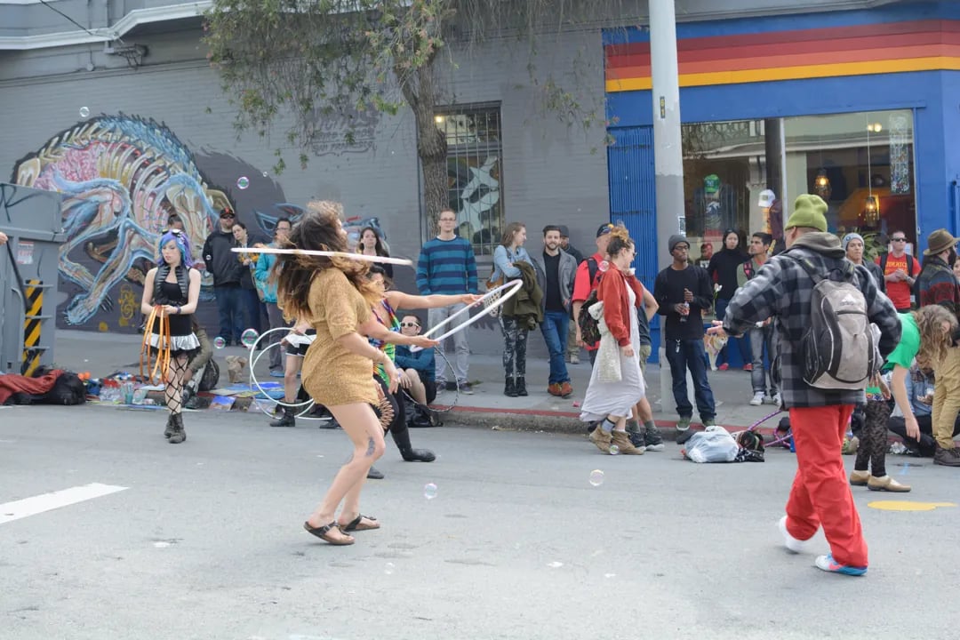 Two women performing a hula hoop act for a crowd on the street at the Haight-Ashbury Street Fair.
