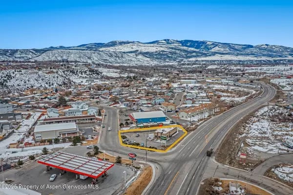 Aerial view of buildings and a yellow-outlined parcel, with snowy mountains in the background.