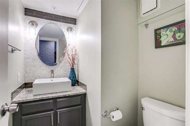 Bathroom with dark vanity, vessel sink, oval mirror, and separate toilet nook.