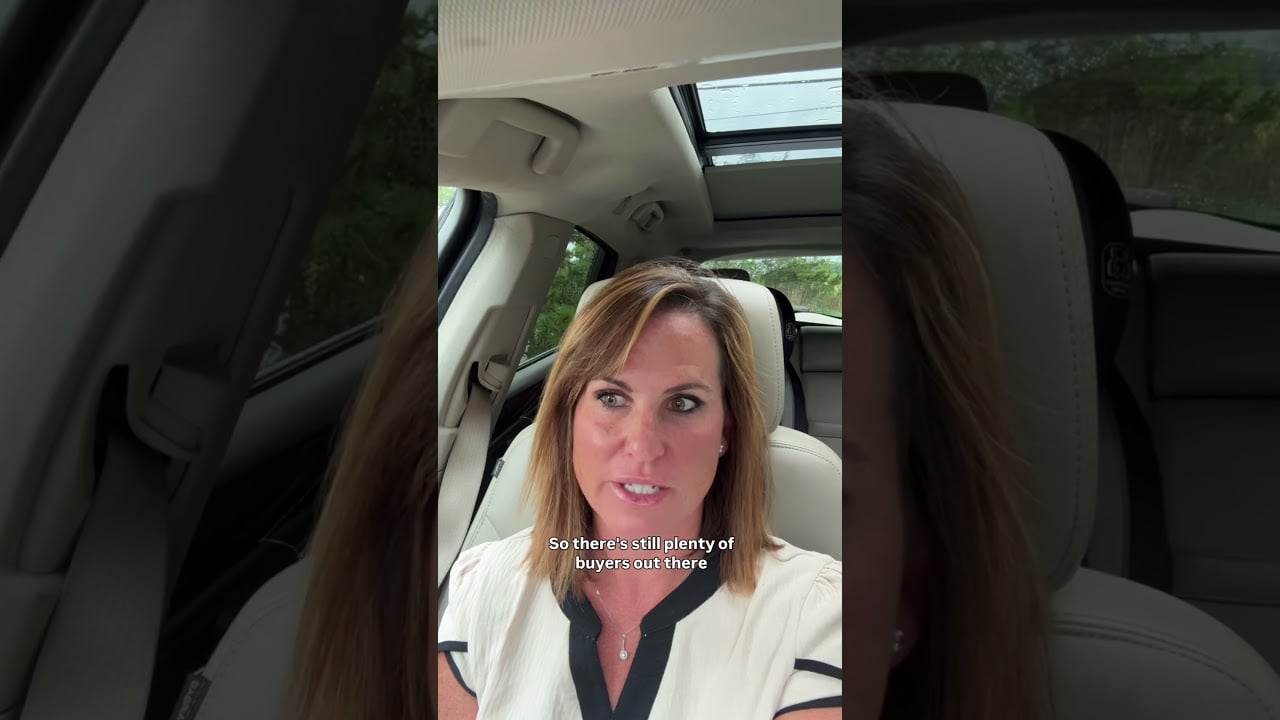 A woman speaking from a car, wearing a white top with black trim.