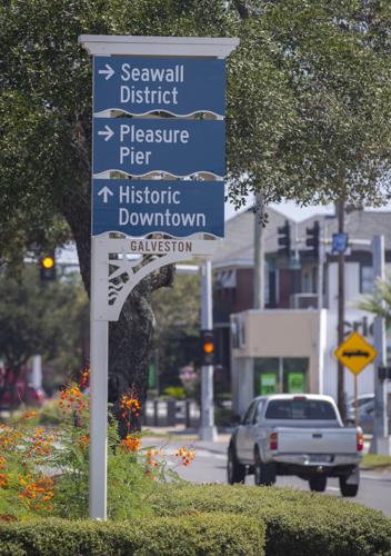 Galveston street sign pointing to the Seawall District, Pleasure Pier, and Historic Downtown.