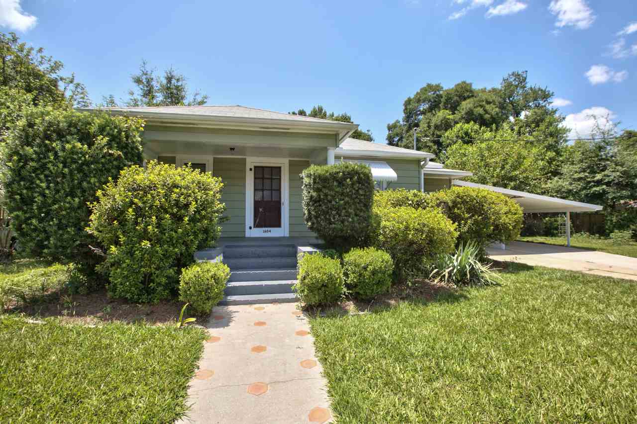 A small house surrounded by lush green grass and vibrant bushes, creating a serene and inviting outdoor space.