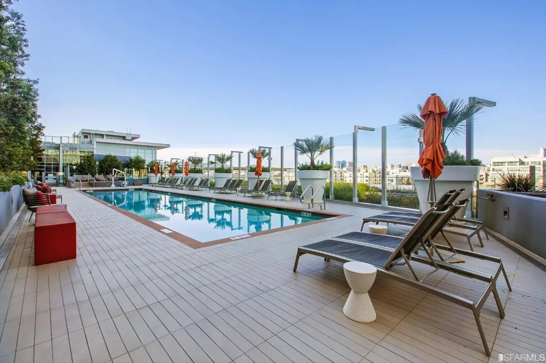 Arden Residences rooftop pool with lounge chairs and a view of the city skyline.