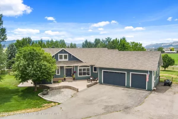 Teal single-story home with a two-car garage, front porch, and distant mountain views.