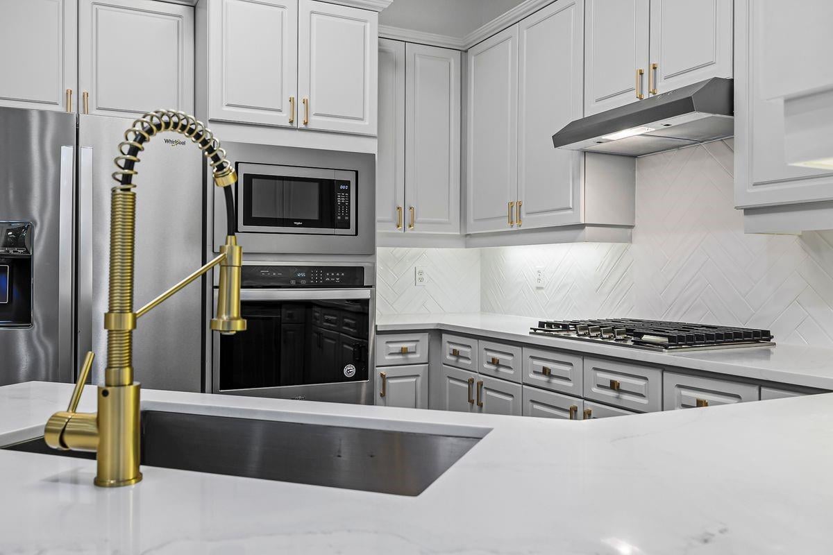 Kitchen detail of the brass pull-down faucet and stainless appliances, Barton Hollow, Westlake, Austin.