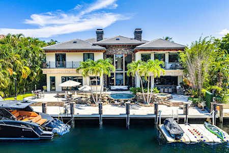 Waterfront home with a pool, dock, and boats along the canal.