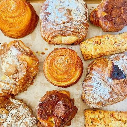 Assorted flaky pastries and danishes arranged on parchment paper