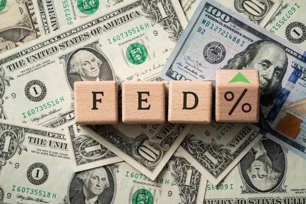Wooden FED% tiles on a spread of U.S. dollar bills.