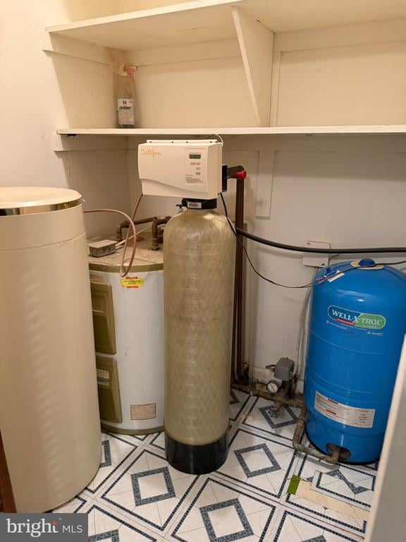 Utility room with water-treatment tanks, a water heater, and geometric floor tiles.