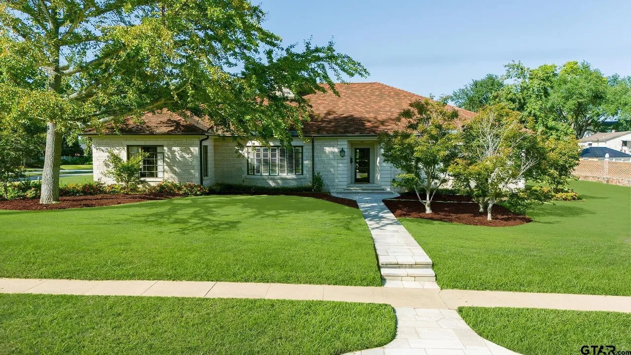 front yard of house with green grass, trees and red tile roof