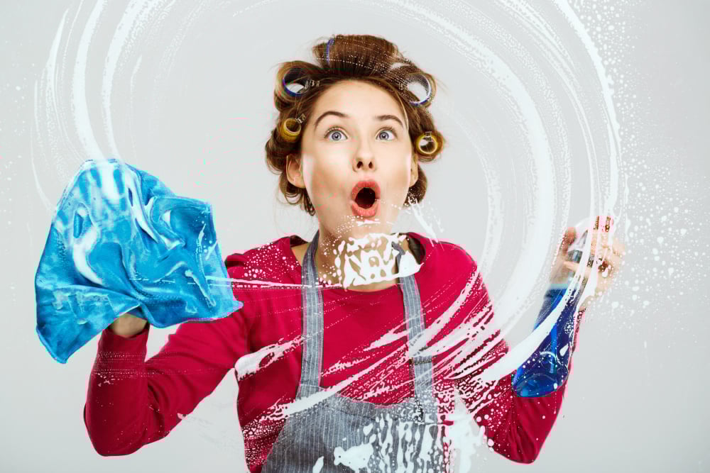 Woman cleaning a glass surface with enthusiasm to ensure a sparkling, fresh look for the Texas spring season.