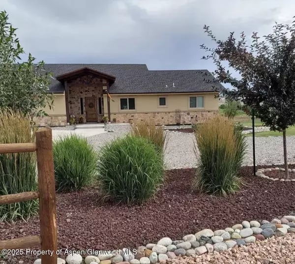 Single-story home with a covered wood entry, stone accents, and landscaped gravel paths.