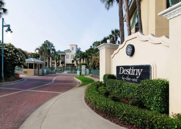Entrance to Destiny by-the-sea with its neighborhood sign and palm-lined road.