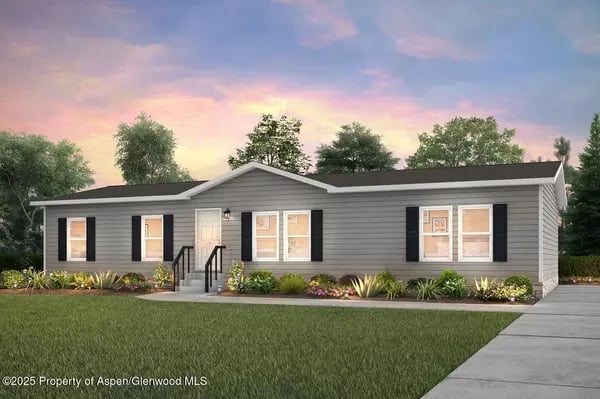 Gray single-story ranch home with black shutters, landscaped flower beds, and a concrete walkway.