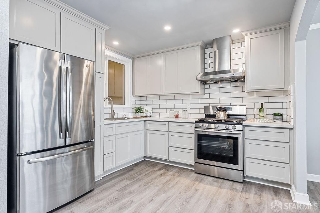 Kitchen with white cabinets, subway tile backsplash, stainless steel appliances, and gray wood-look flooring.