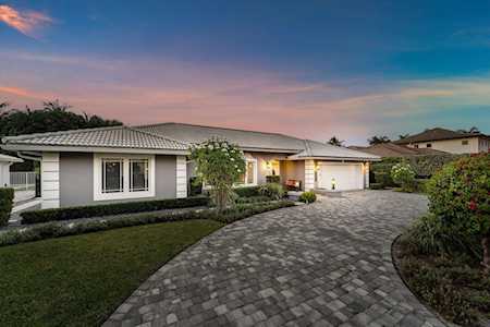 Single-story white home with a curved paver driveway and landscaped front yard at dusk.