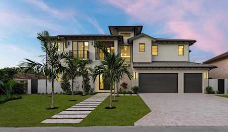 Contemporary two-story home with a two-car garage, palm trees, and a stepping-stone path at dusk.