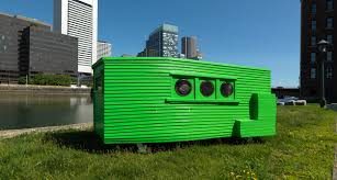 Bright green corrugated structure with three round windows on a grassy lot.
