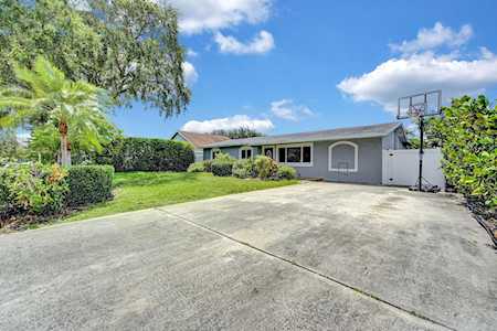 Single-story gray home with a wide concrete driveway and basketball hoop.