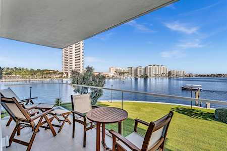 Condominium balcony with wooden seating overlooking the water and waterfront high-rises.