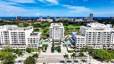 Coastal condominium buildings in East Boca with landscaped grounds, ocean, and distant skyline.