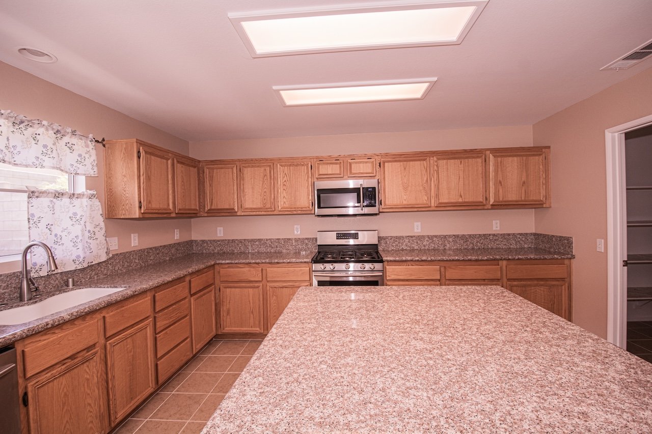 Kitchen with oak cabinetry, granite countertops, a large island, and stainless steel appliances.